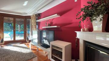 Un salon avec une télévision, une cheminée et un mur rouge.