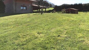 A large grassy field with a building that has a red roof and a small red structure nearby. - Rural house (full rental) Chalet in Arcentales for 12 people (Arcentales)
