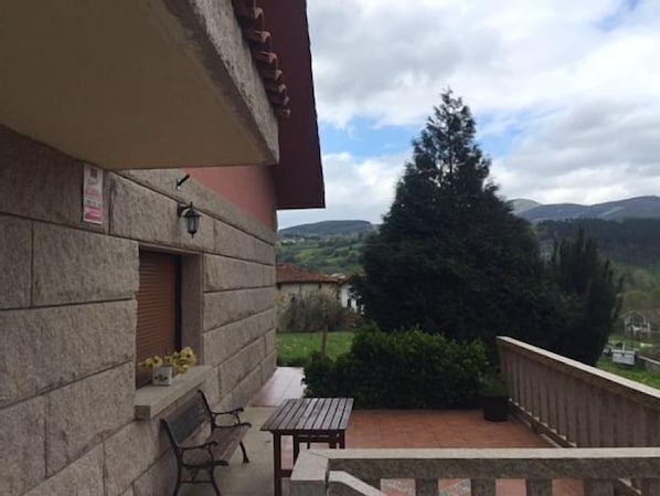 Un balcon avec un mur en pierre, une table en bois et un banc.