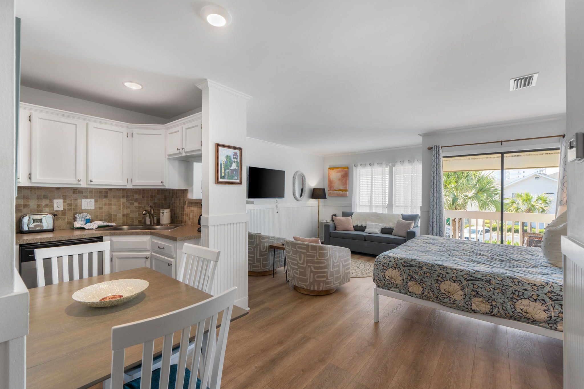 A compact living space with a kitchenette, a dining area, a sofa, and a bed.