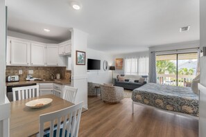 A compact living space with a kitchenette, a dining area, a sofa, and a bed.