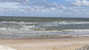 A beach with waves and a cloudy sky.