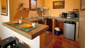 A compact kitchen with a central island, a microwave, and a refrigerator. - Big Bend Bungalow A (TERLINGUA)