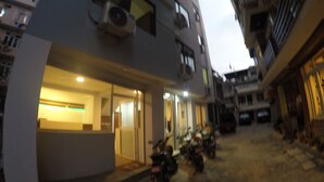 A building with multiple floors, air conditioning units, and a few parked motorcycles. - Bodhi Tree Hostel (Kathmandu)