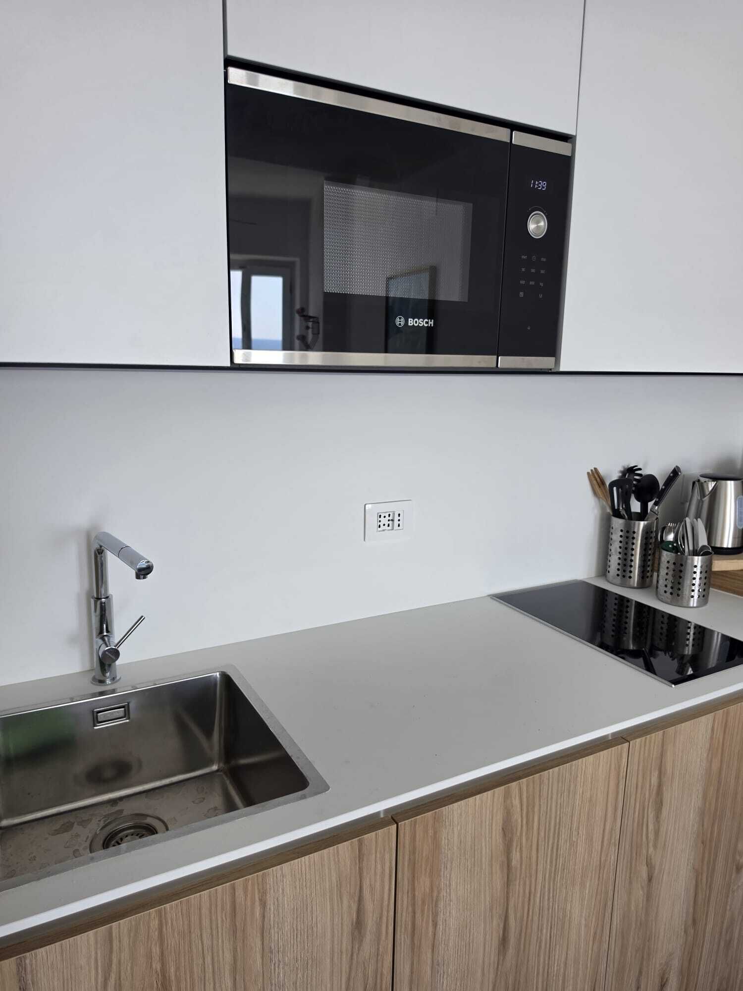 A kitchen with a stainless steel sink, a Bosch microwave, and a knife holder.