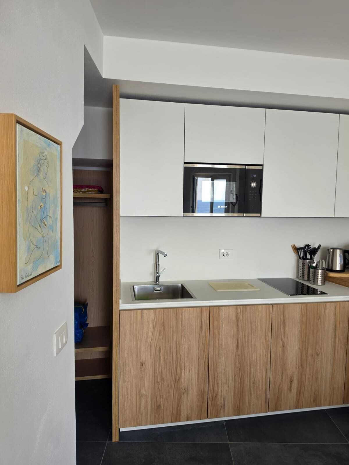 A modern kitchen with a built-in microwave, a sink, and wooden cabinetry.