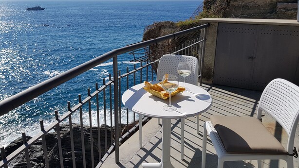 Een balkon met een tafel en stoelen, met uitzicht op de oceaan.