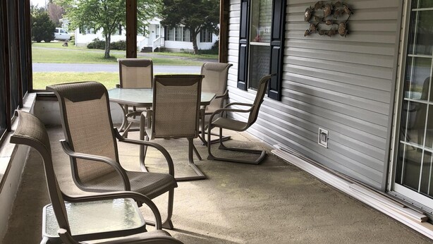 A covered patio area with metal chairs and a table, a ceiling fan, and a view of a residential street. - Single family home - Less than 4 miles from Rehoboth Beach Boardwalk (Rehoboth Beach)
