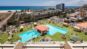 A hotel with a large pool area, multiple swimming pools, and a beach view. - Apartments Palm Garden (Morro Jable)