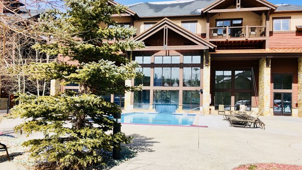 A lodge with a pool, large windows, and a stone facade.