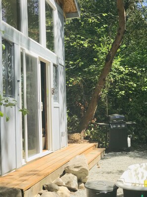 A modern house with large windows, a wooden deck, and a barbecue grill.