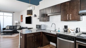 Une cuisine moderne avec des meubles de rangement de couleur sombre, un lave-vaisselle encastré et un four à micro-ondes.