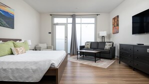 Une chambre d’hôtel moderne avec un grand lit, un canapé, une télévision et une fenêtre avec des rideaux.