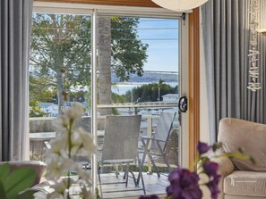 A room with a sliding glass door leading to a balcony, a sofa, and a table with chairs.
