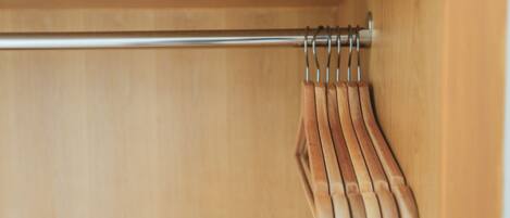 A wooden closet with a metal rod and wooden hangers.