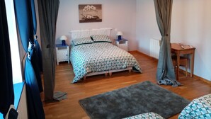 Une chambre à coucher comprenant un lit, deux tables de chevet, une commode, une petite table et une chaise.