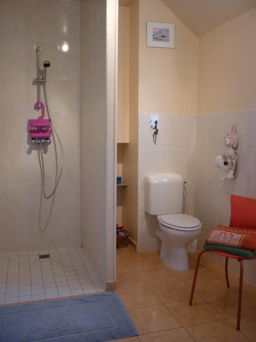 Un baño con ducha, inodoro y una silla.