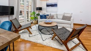 Ein modernes Wohnzimmer mit einer Couch, zwei Sesseln, einem Couchtisch und einem Fernseher.