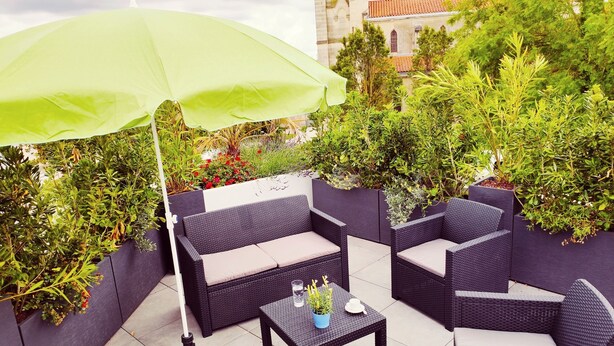 Un patio al aire libre con mobiliario de mimbre, una mesa y una sombrilla.