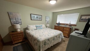 A bedroom with a bed, dresser, desk, and a computer. - Riverwalk Condominiums #11 – Ground Floor with Private Patio, Close to Beach and (Seaside)