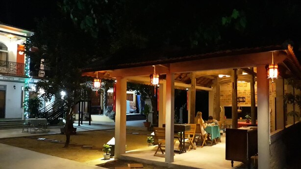 An outdoor dining area with tables and chairs, a covered seating area, and a staircase leading to an upper level. - Tropical Valley Homestay (Phong Nha)