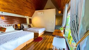 A room with two beds, a wooden ceiling, a small table, and a view of greenery through the window. - Tropical Valley Homestay (Phong Nha)