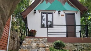 A small house with a stone staircase, a small garden, and a pond in the foreground. - Tropical Valley Homestay (Phong Nha)