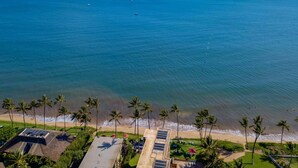 Vista aérea de una propiedad costera con playa, palmeras y zona de piscina.