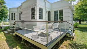 A white house with a covered deck and outdoor seating area. - Sleepy Hollow Beach Resort, Cottage 6A – Family Fun on Lake Michigan! (South Haven)