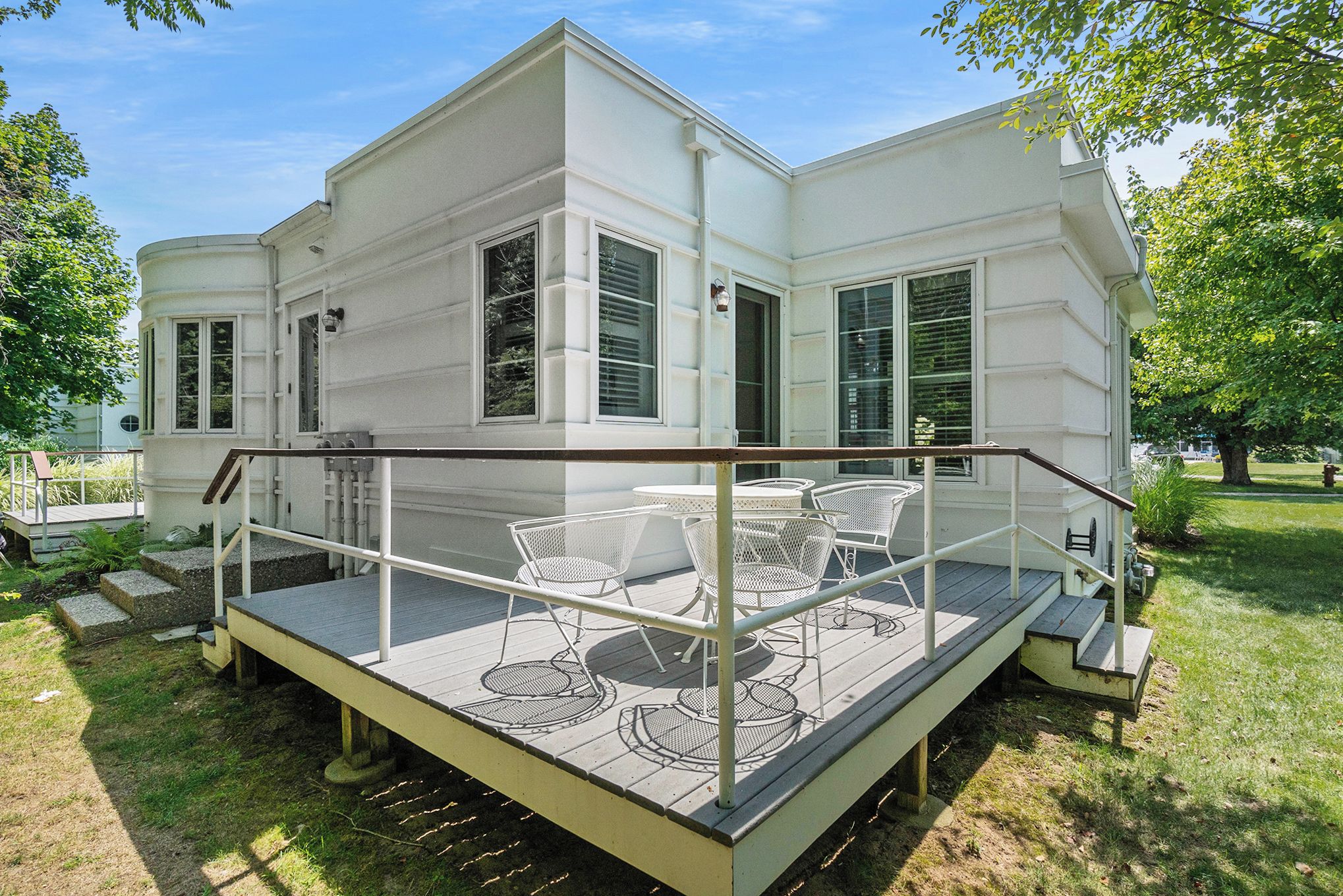 Ein weißes Haus mit überdachter Terrasse und Sitzbereich im Freien.