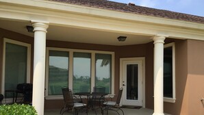 A covered patio with a table and chairs, large windows, and a door. - The Seahorse- 7 Hac (Laguna Vista)