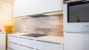 A modern kitchen with a built-in stove, white cabinetry, and a stone backsplash. - Separate, comfortable house for 6-8 guests - 3 bedrooms, 3 bathrooms (Bad Sachsa)