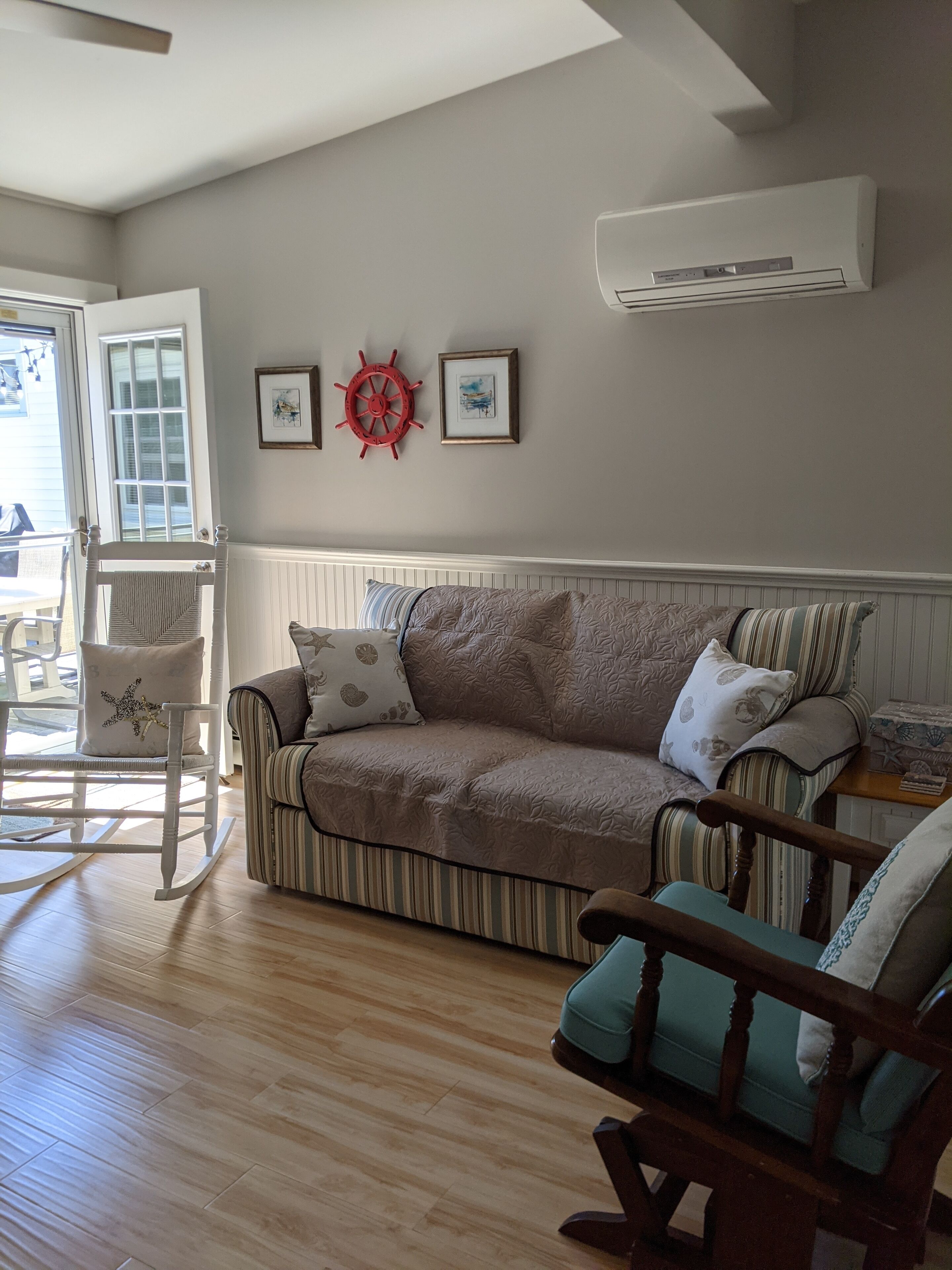 A cozy living room with a striped sofa, a rocking chair, and a wooden floor.