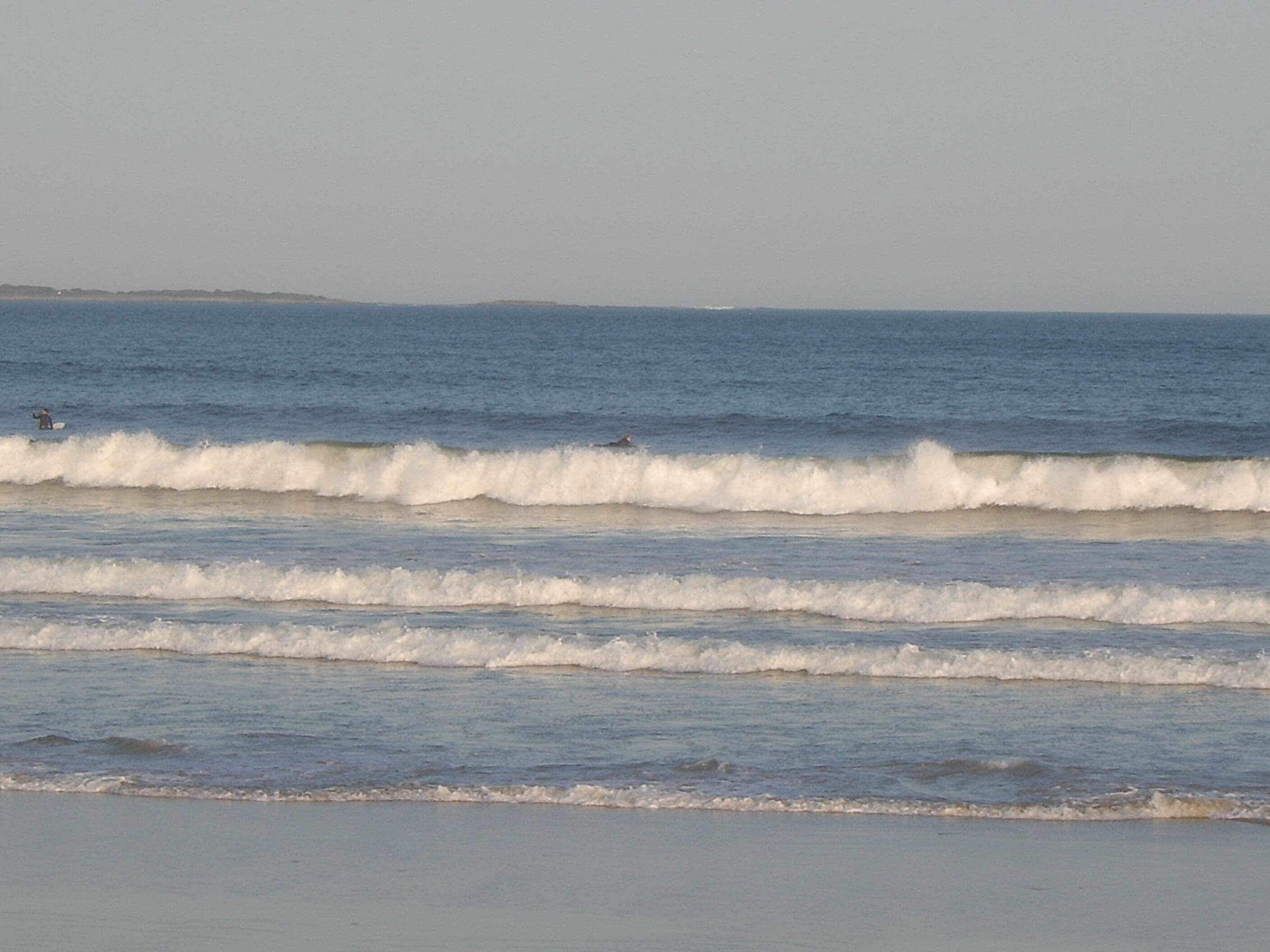 A beach with waves and a distant shoreline.