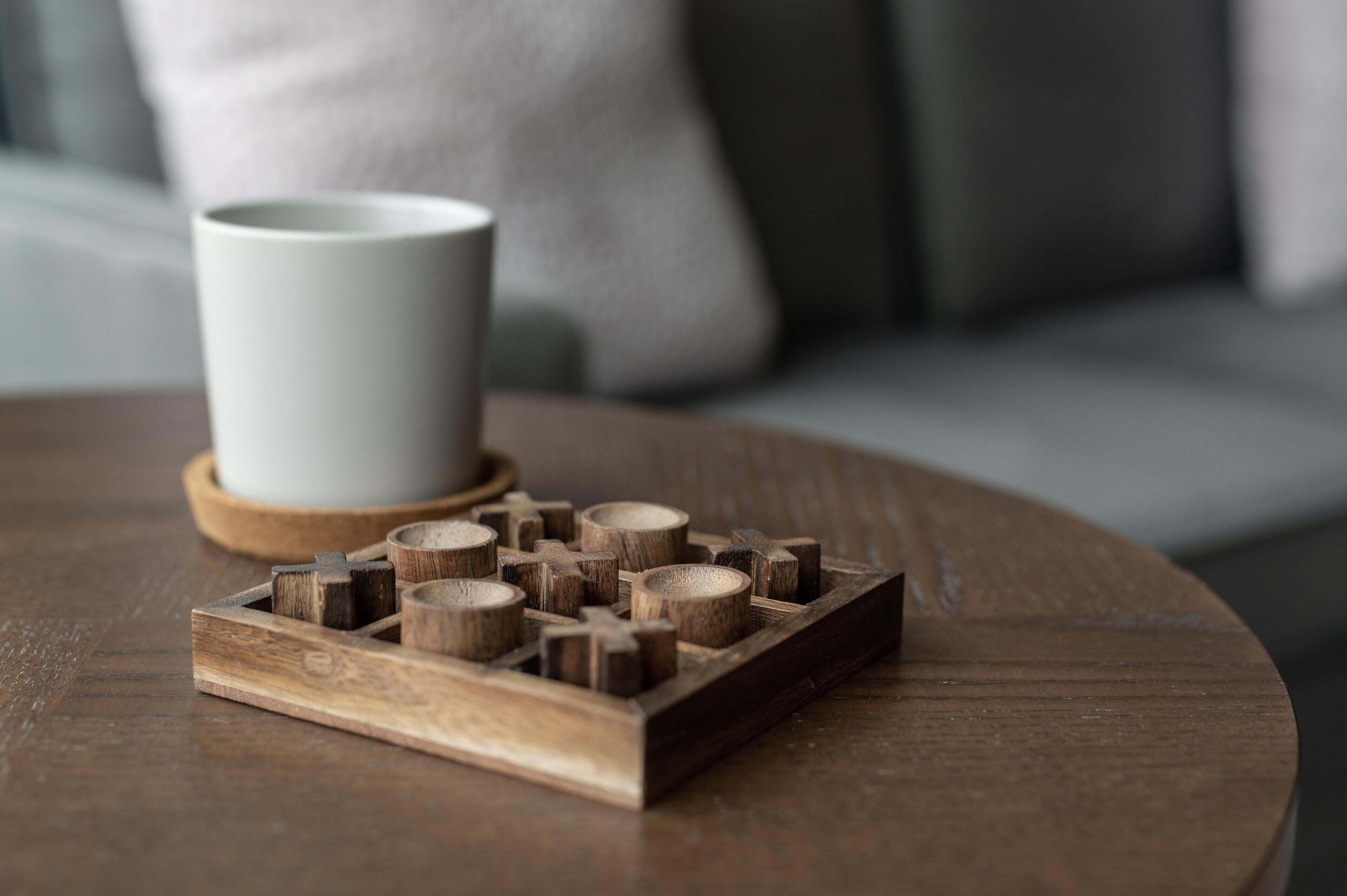 A wooden tray with a white mug on a round wooden table.