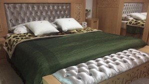 Una camera da letto con una testiera trapuntata, una coperta verde e una panca decorata ai piedi del letto.