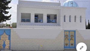Un edificio moderno con facciata bianca, una cupola blu e una porta decorata in blu.