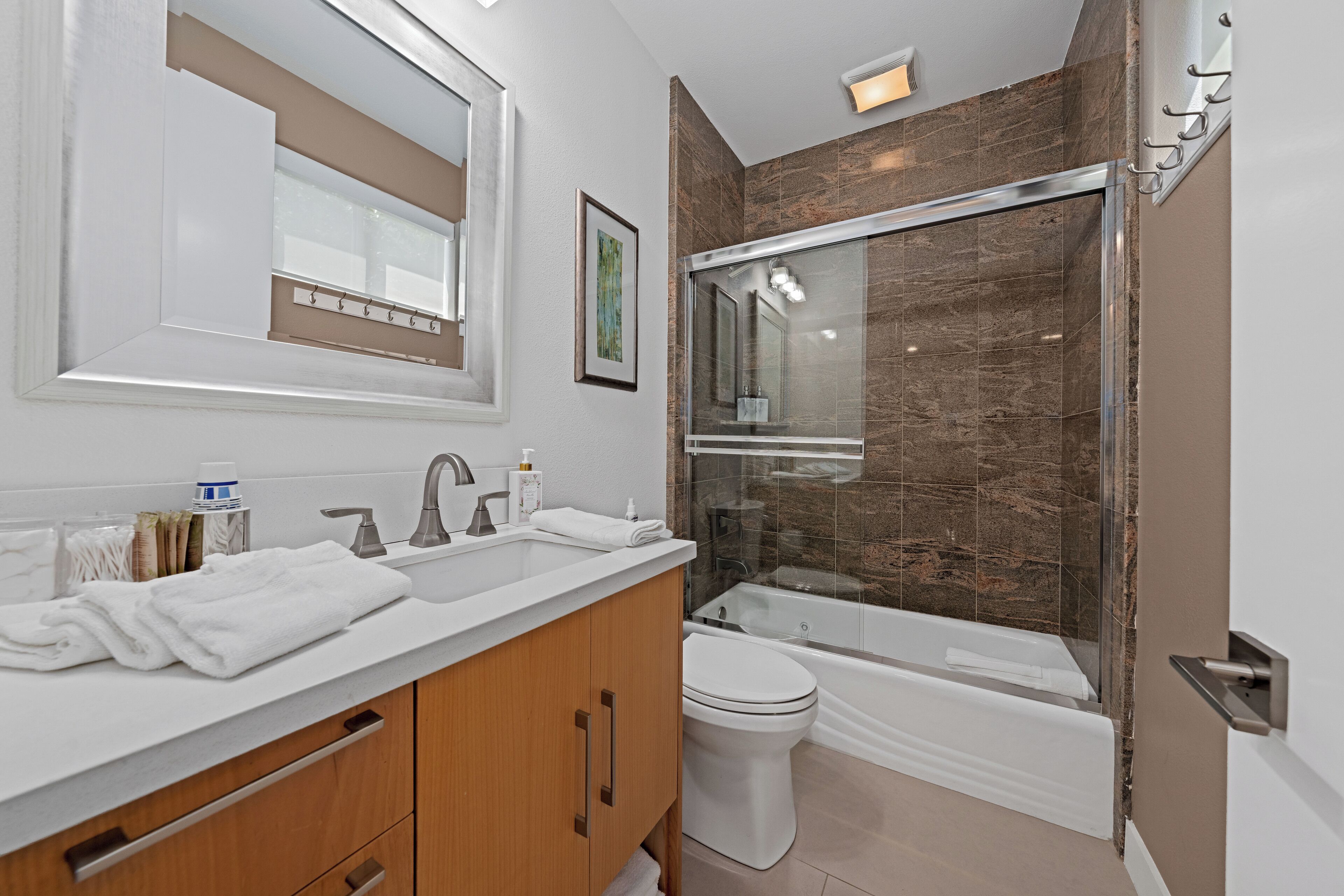 Een moderne badkamer met een wastafel met dubbele wastafel, een toilet en een douche met glazen wanden.