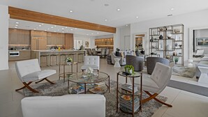 Un vaste espace de vie aménagé avec des meubles modernes, une cuisine à l’arrière-plan et une étagère décorative.
