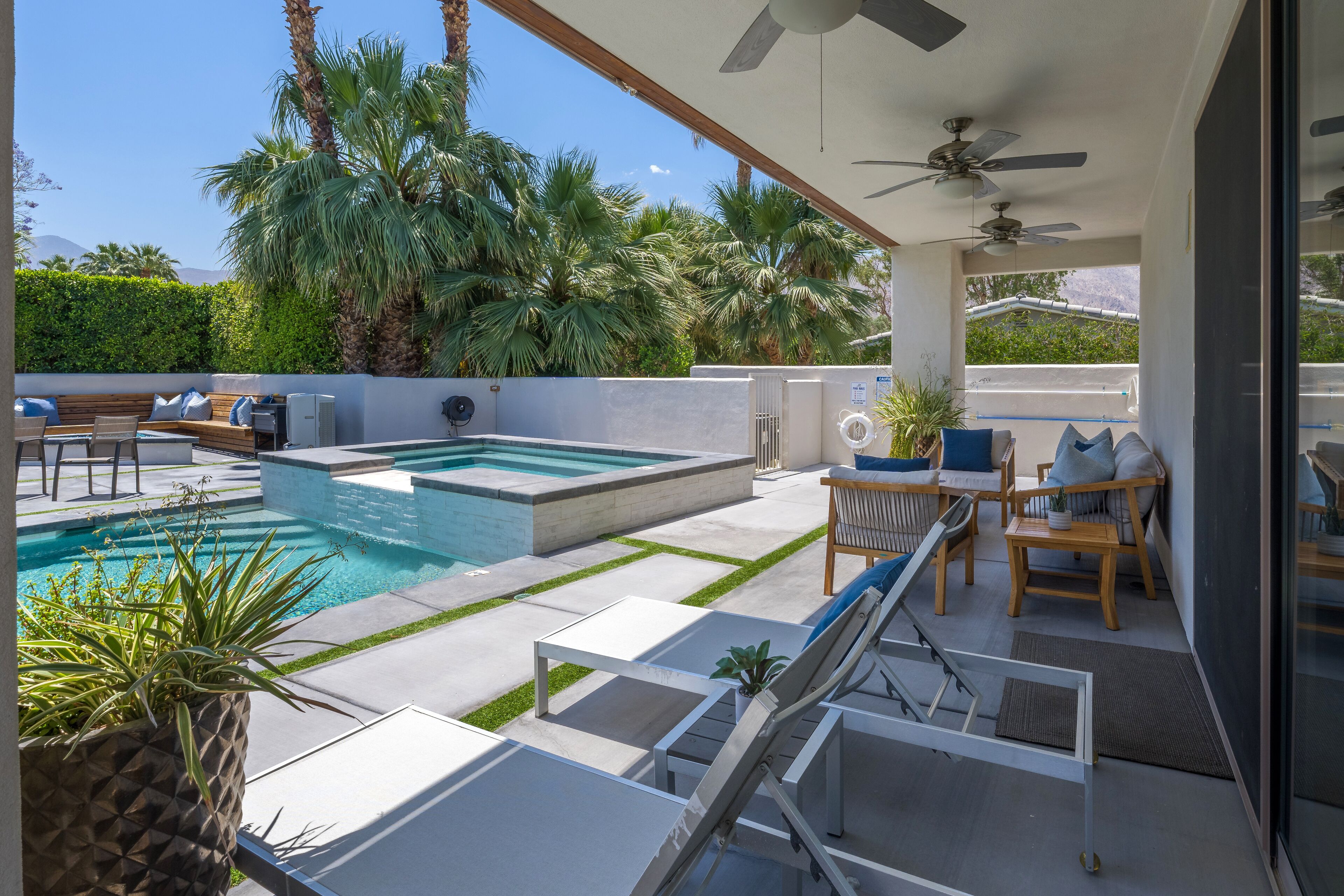 Un espace piscine aménagé sur le toit, avec un jacuzzi, des chaises longues et des ventilateurs de plafond.