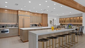 Une cuisine moderne dotée d’un grand îlot central, de tabourets de bar et de meubles de rangement en bois.