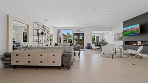 Un salon moderne doté d’un grand téléviseur, d’une cheminée et d’un coin repas.