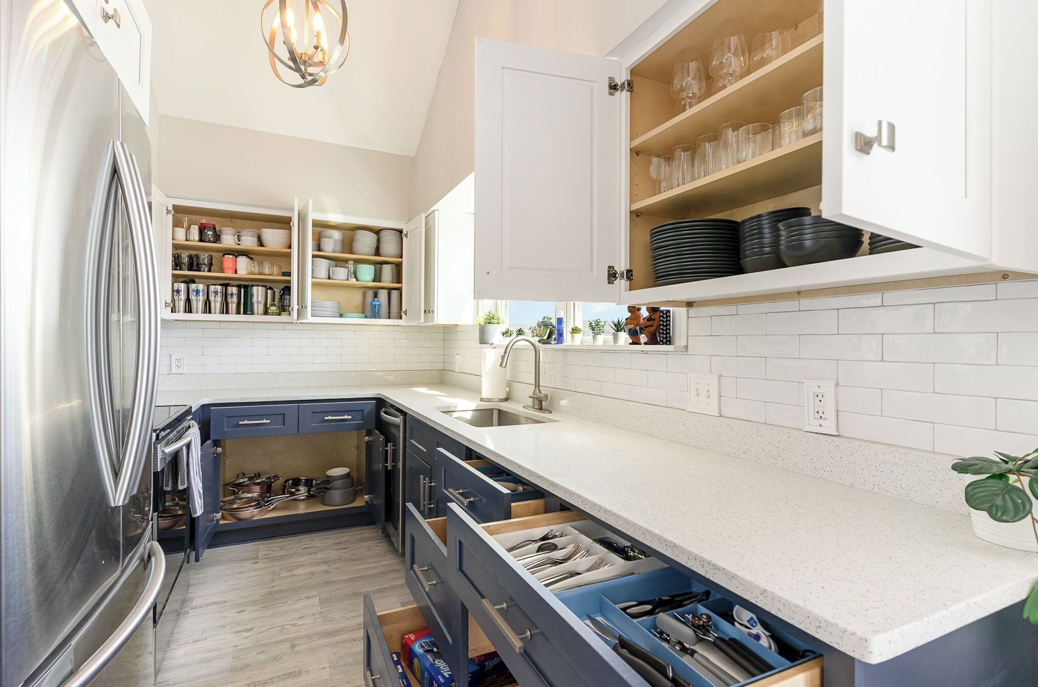 Een moderne keuken met witte kasten, een roestvrijstalen koelkast en een aanrecht met een spoelbak.