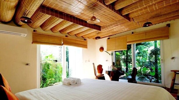 A bedroom with a large bed, bamboo ceiling, and large windows offering a view of greenery. - Mercy Homestay - Experience Vietnam rural life (Individual) (Hội An)
