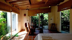 A room with a bed, a shower, a table with chairs, and a view of greenery outside. - Mercy Homestay - Experience Vietnam rural life (Individual) (Hội An)