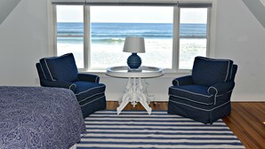 A bedroom with a view of the ocean, two blue armchairs, a white table with a lamp, and a striped rug. - Luxury Oceanfront 5 Bedroom 3.5 Bathroom Private Parsons Beachfront Paradise (Kennebunk)