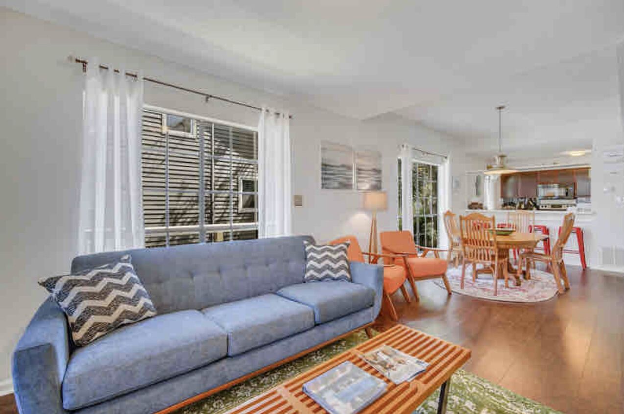 A living room with a sofa, coffee table, and dining area with chairs and a table.