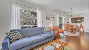 A living room with a sofa, coffee table, and dining area with chairs and a table. - The Fairy Tern, PRIVATE/ONE-OF-A-KIND 4bd/3bth on Tybee's North End (Tybee Island)
