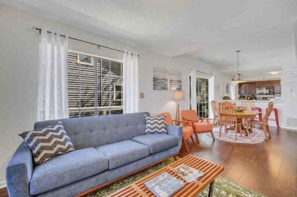 A living room with a sofa, coffee table, and dining area with chairs and a table. - The Fairy Tern, PRIVATE/ONE-OF-A-KIND 4bd/3bth on Tybee's North End (Tybee Island)