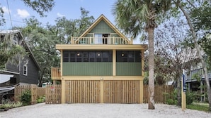A two-story building with a balcony, a fenced driveway, and a palm tree. - The Fairy Tern, PRIVATE/ONE-OF-A-KIND 4bd/3bth on Tybee's North End (Tybee Island)